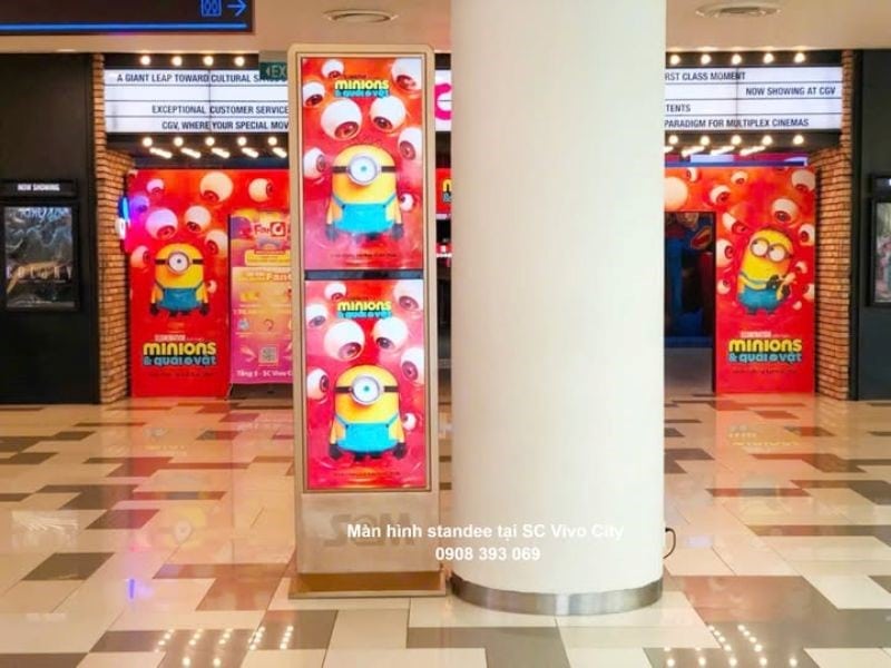 Màn hình LCD dạng standee kỹ thuật số đặt tại khu vực hành lang gần rạp chiếu phim, phù hợp quảng bá phim, sản phẩm và chương trình khuyến mại.